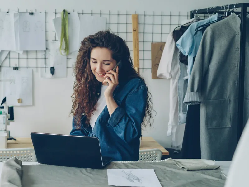 Inhaberin eines kleinen Ateliers mit Laptop und Telefon